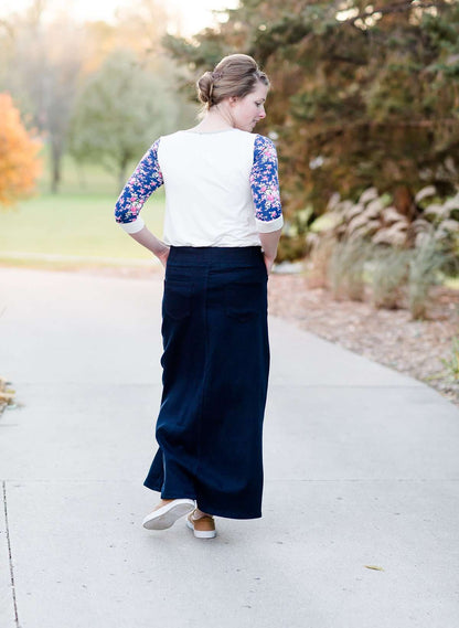 Woman wearing a raglan baseball style top. The shirt is gray with contrasting navy and pink floral sleeves.