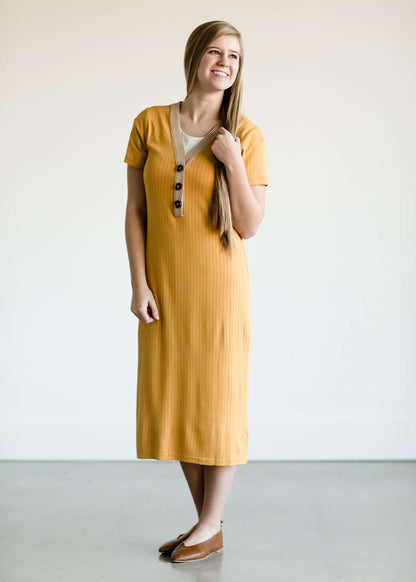 Woman wearing a ribbed mustard midi dress with faux wood buttons.