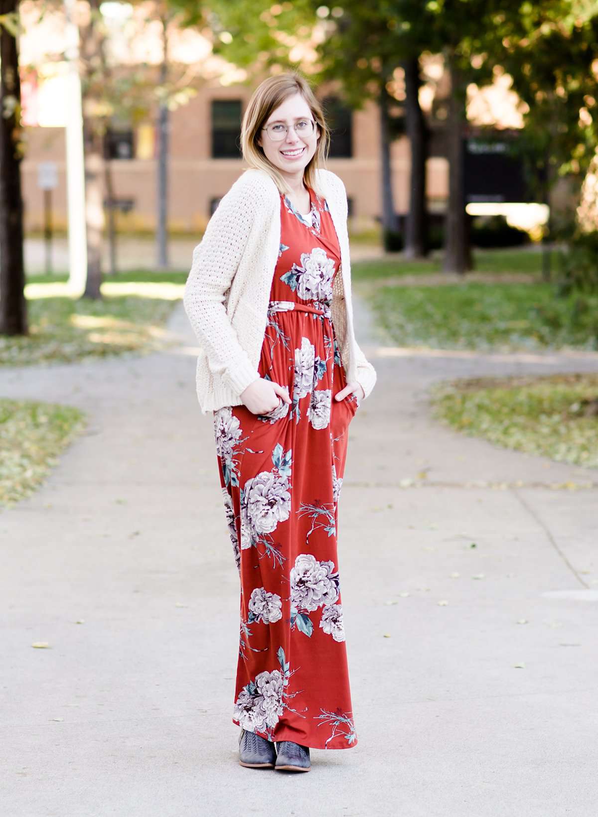 Young woman wearing a ivory chunky knit acrylic and wool sweater. This sweater has front pockets and features an open front.