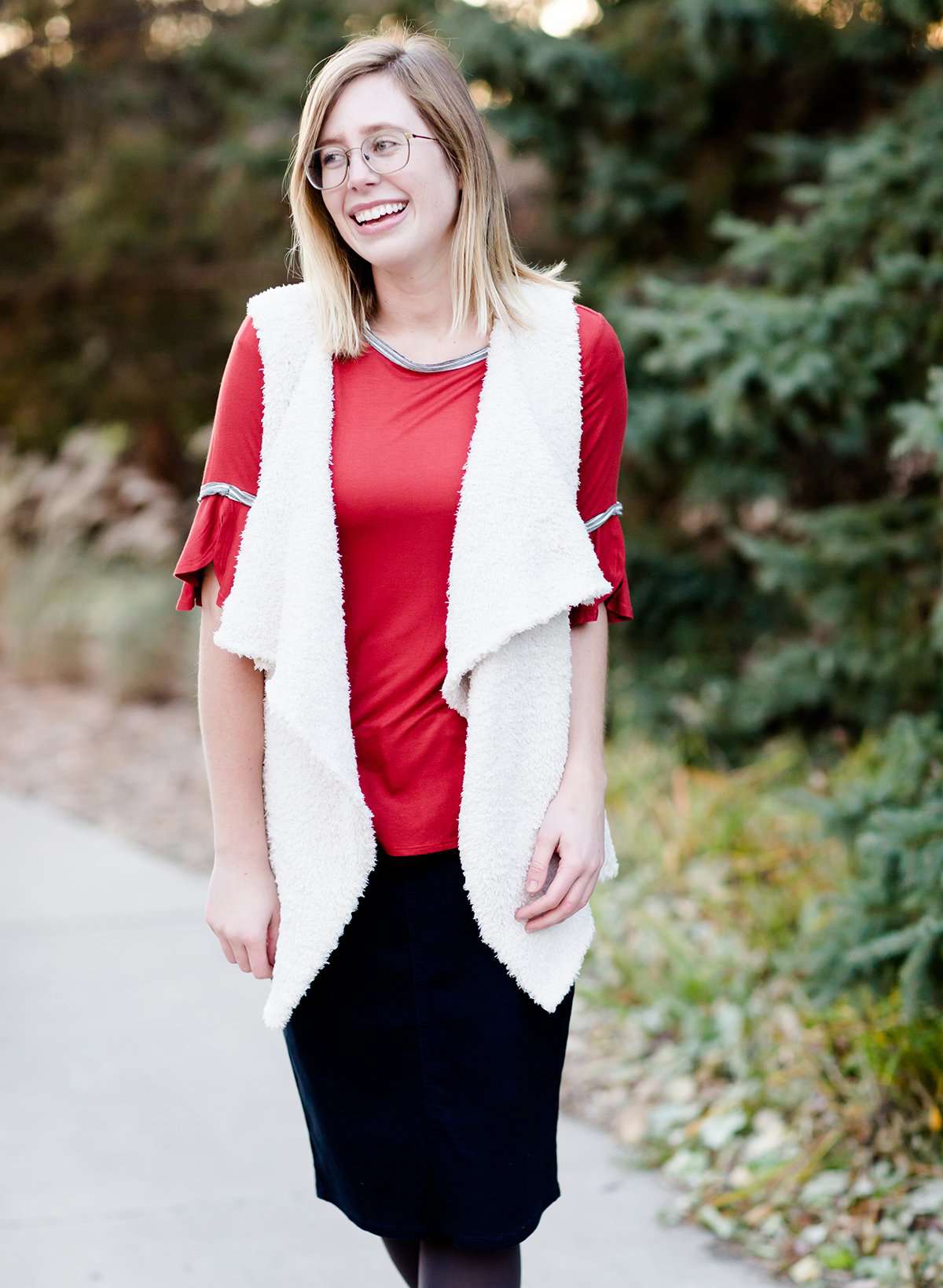 Woman wearing a rust colored, modest bell sleeve top. The 3/4 sleeves flutter and the top is also lined.