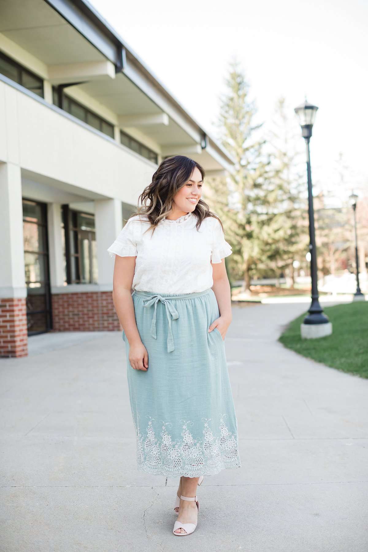 Woman wearing a mint green cotton midi skirt with a self tie and feminine crochet lace detail at the bottom hem