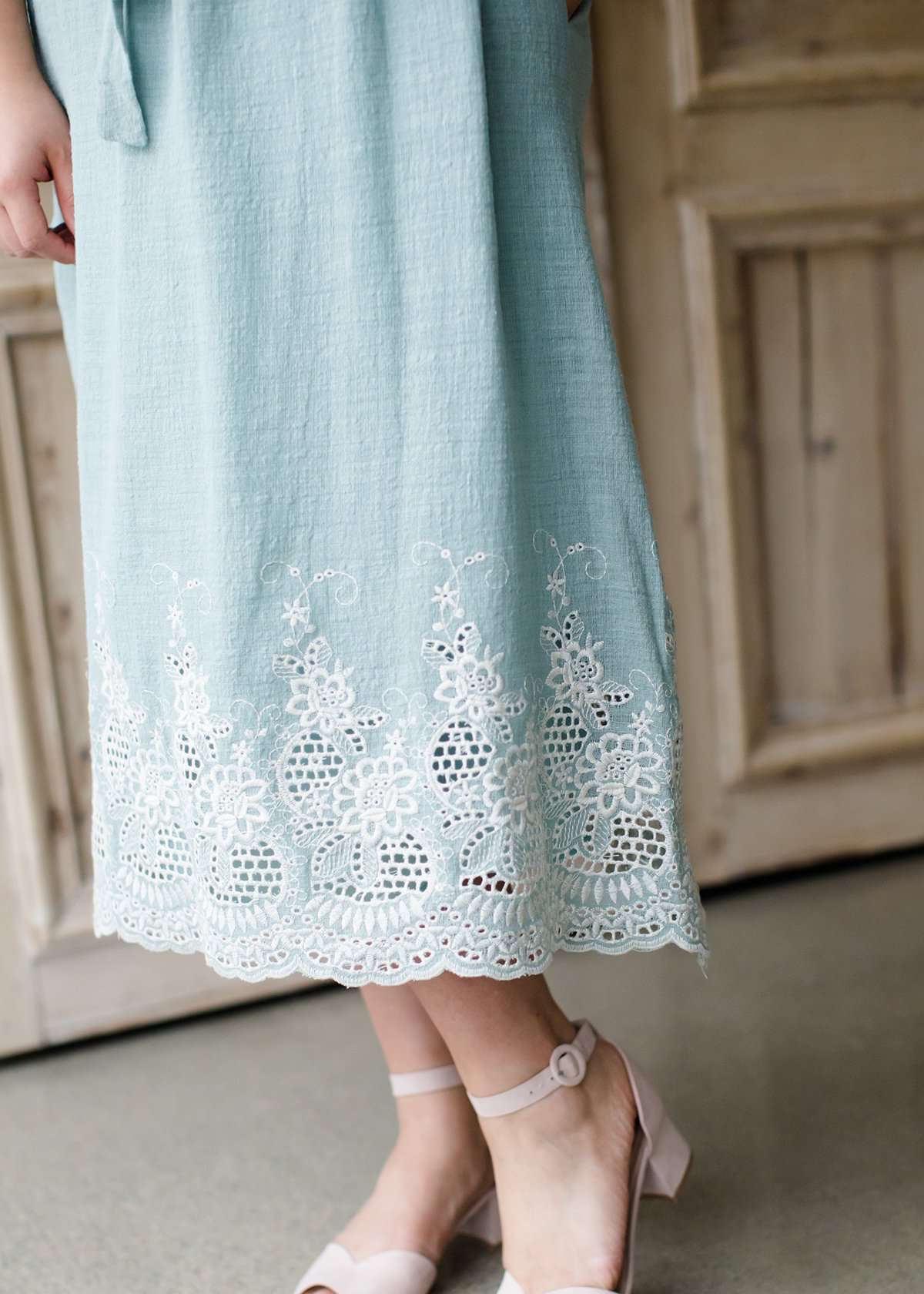 Woman wearing a mint green cotton midi skirt with a self tie and feminine crochet lace detail at the bottom hem