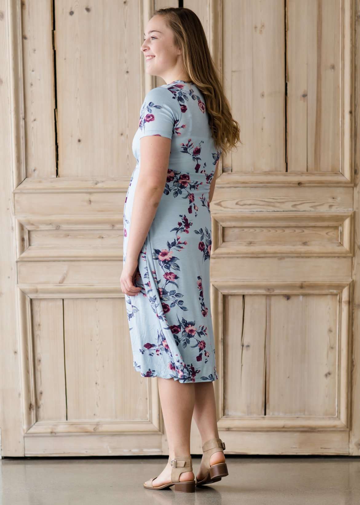 Woman wearing a light blue modest empire waist midi dress with flowers on it