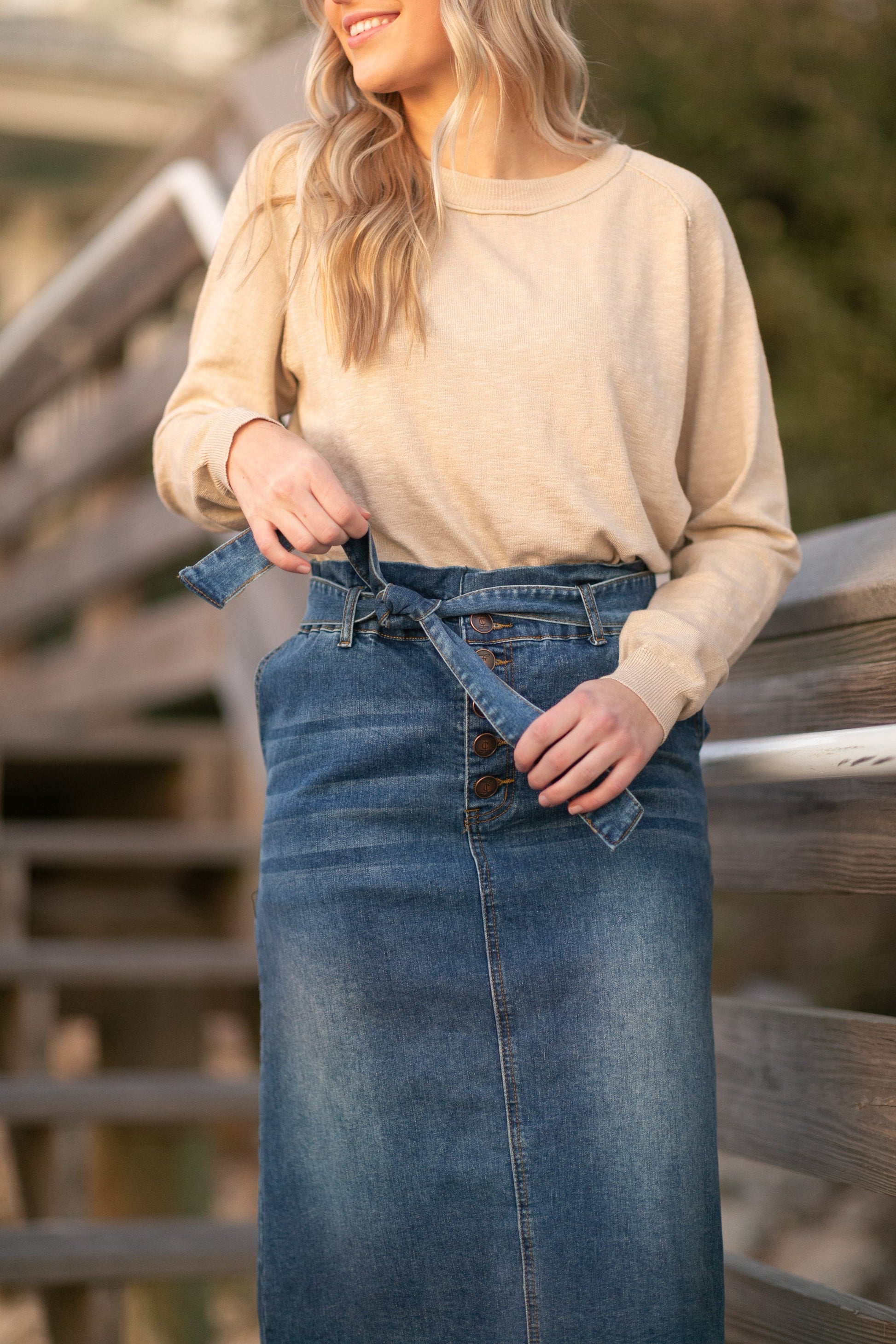 This midi length skirt is made out of stretch denim, with a paperbag stretch waist, with a matching belt, and a raw hem.