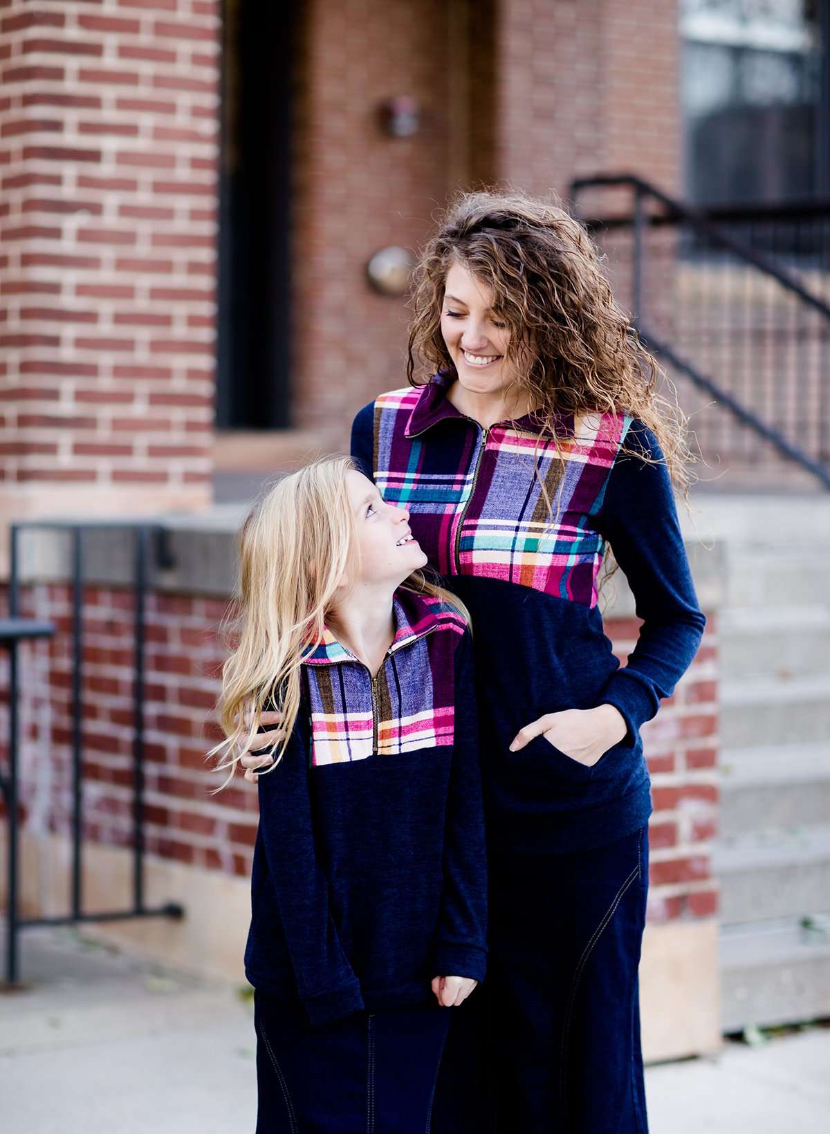 This half zip pullover features a front pouch pocket and a beautiful color block print of fuchsia, teal and mustard!  This young girl is also matching her mother in a mommy and me style.