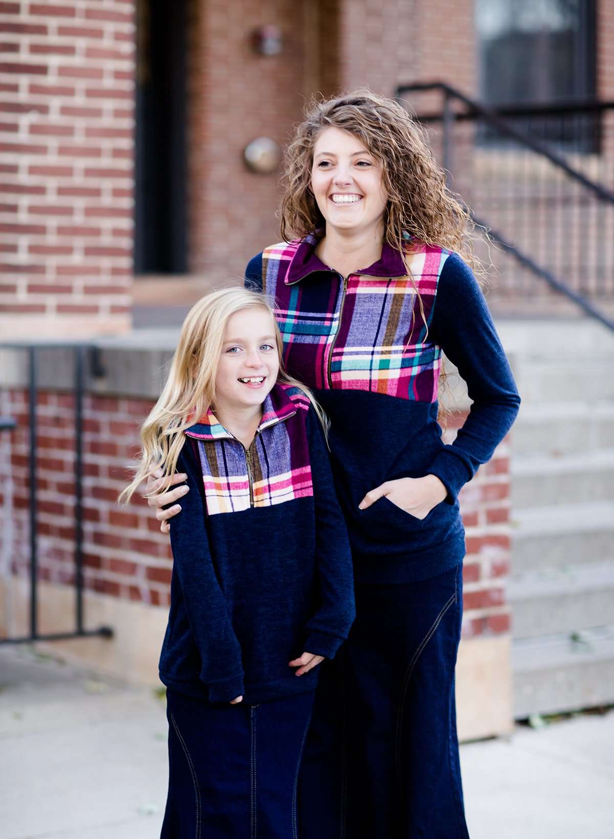 This half zip pullover features a front pouch pocket and a beautiful color block print of fuchsia, teal and mustard!  This young girl is also matching her mother in a mommy and me style.